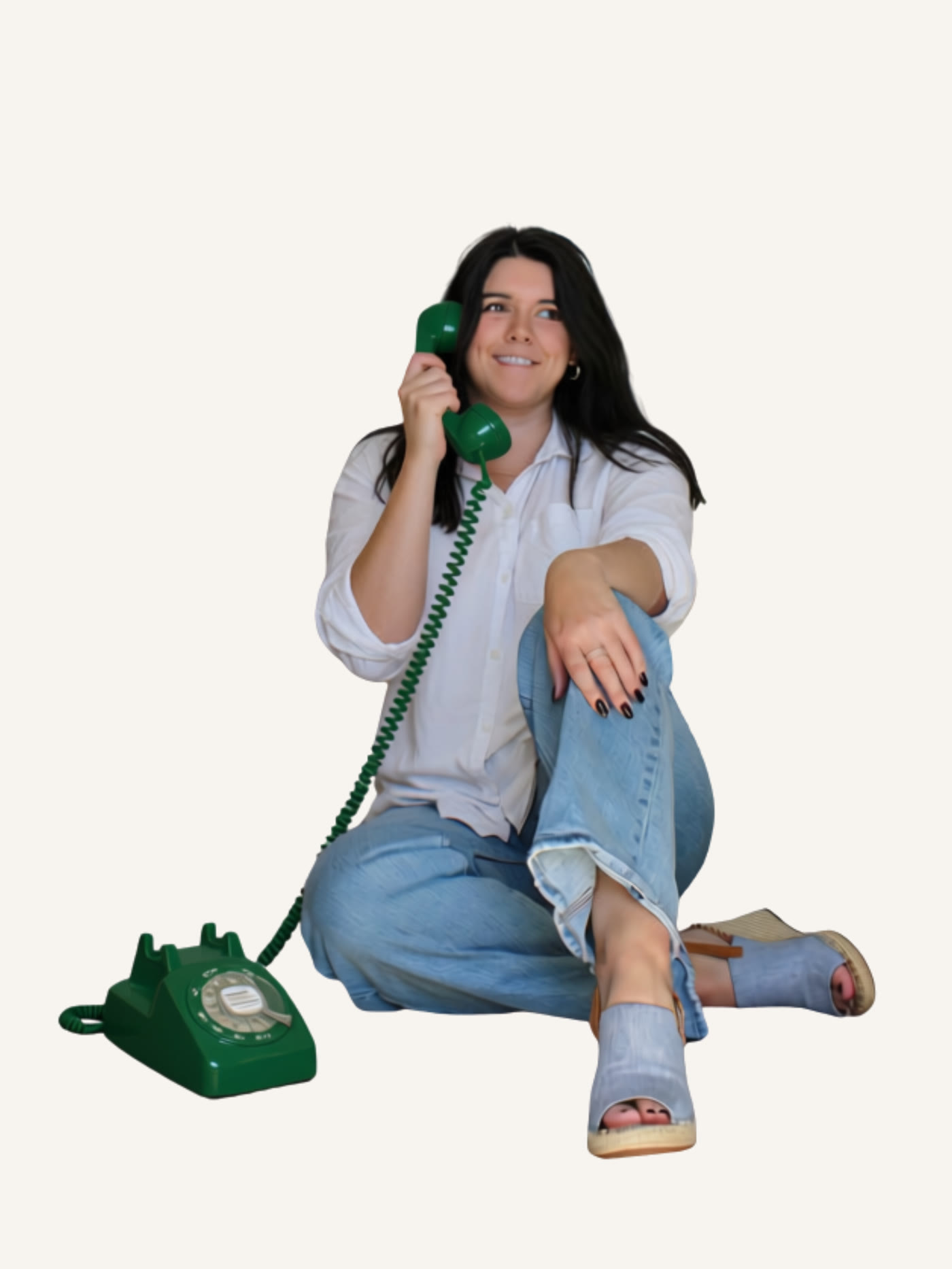 Elizabeth Craig, founder of Social Centre, sitting on the floor and smiling while talking on a green rotary phone